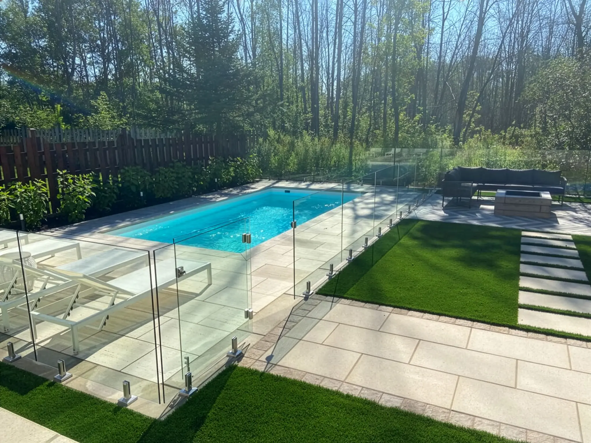 Piscine entourée de pavé uni grand format avec clôture de verre et gazon artificiel, Boucherville